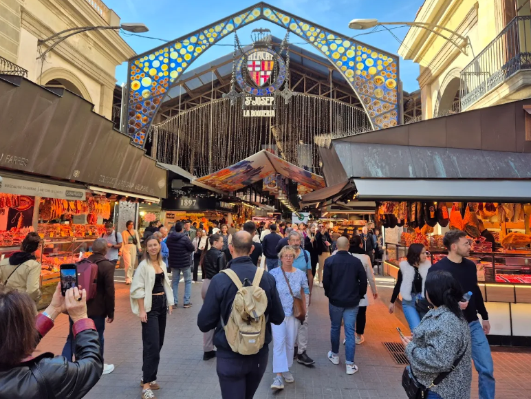 Entrada do Mercat de la Boqueria em Las Ramblas, Barcelona, com visitantes e bancas de alimentos frescos