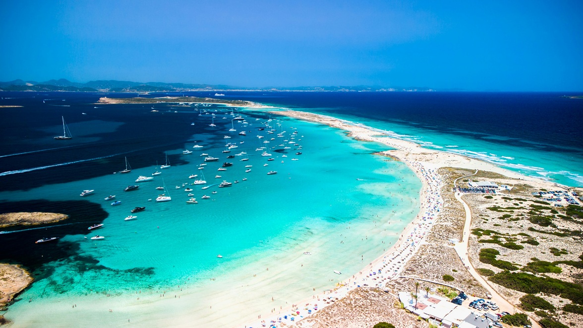 Vista aérea de las playas paradisíacas de Formentera con aguas cristalinas turquesas y barcos anclados - Islas Baleares, España