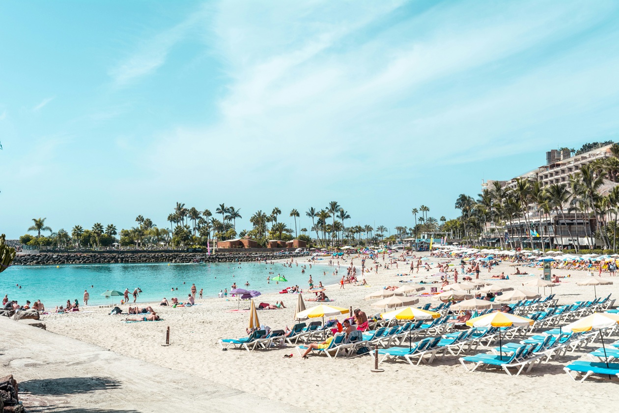 Playa paradisíaca en las Islas Canarias con aguas turquesas, palmeras y tumbonas - España